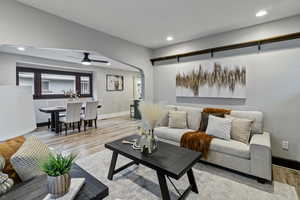 Living room featuring light wood-style floors, recessed lighting, arched walkways, and a ceiling fan