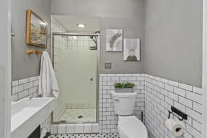 Bathroom featuring tile walls, vanity, a shower stall, and wainscoting