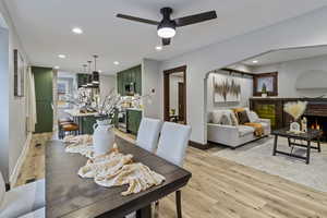 Dining space with light wood-style floors, recessed lighting, ceiling fan, and a brick fireplace