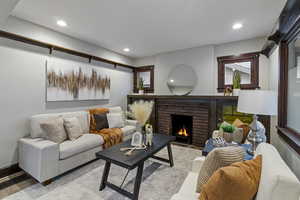Living room featuring a brick fireplace, recessed lighting, and wood finished floors