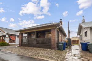 View of front of house with brick siding, a chimney, and covered porch