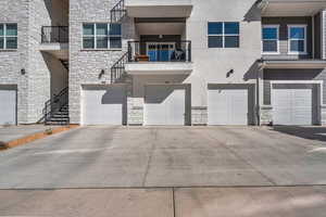 View of front facade with stone siding, a balcony, and a garage