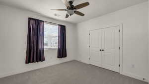 Unfurnished bedroom featuring carpet floors, a ceiling fan, and a closet