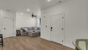Living area with light wood-style floors, ceiling fan, and recessed lighting