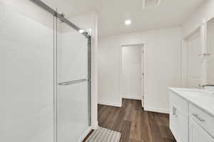 Full bath with vanity, dark wood-style floors, a stall shower, and recessed lighting