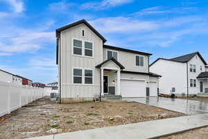 View of front facade featuring board and batten siding, a garage, and driveway