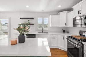 Kitchen with stainless steel appliances, white cabinetry, dark wood finished floors, decorative backsplash, and recessed lighting