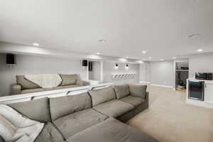 Living room with light carpet, recessed lighting, a textured ceiling, and wine cooler