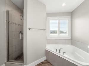 Bathroom with a stall shower, a garden tub, light wood-type flooring, and recessed lighting