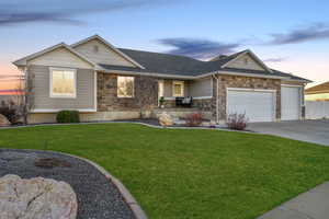 Craftsman-style home featuring stone siding, a garage, a front yard, and covered porch