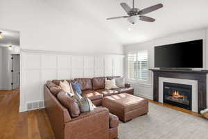 Living area featuring hardwood / wood-style floors, a glass covered fireplace, ceiling fan, and lofted ceiling