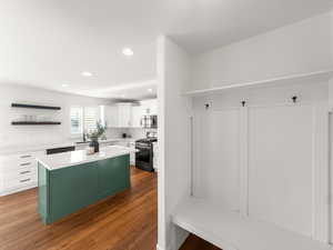 Kitchen with stainless steel appliances, open shelves, a center island, recessed lighting, and two tone color scheme