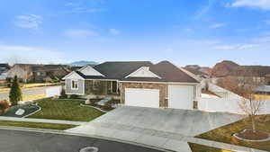 View of front facade with a residential view, an attached garage, concrete driveway, and stone siding