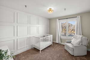 Bedroom featuring dark colored carpet and a nursery area