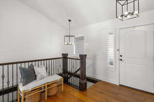 Entrance foyer featuring a chandelier, lofted ceiling, and dark wood-type flooring