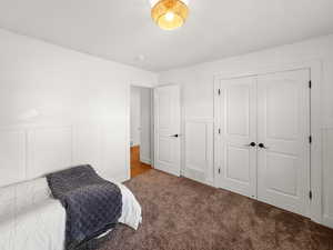 Bedroom featuring wainscoting, a decorative wall, carpet flooring, and a closet