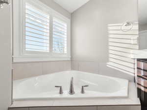 Full bath featuring a garden tub and lofted ceiling