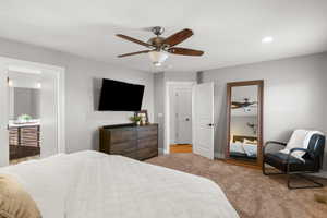 Bedroom featuring light carpet, a ceiling fan, and ensuite bathroom