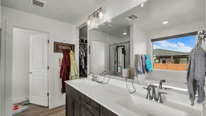 Bathroom with double vanity and dark wood-style floors