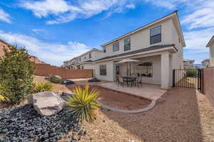 Back of house featuring a patio area, stucco siding, a fenced backyard, and a gate