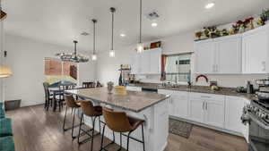 Kitchen with white cabinetry, dark stone counters, a kitchen bar, a center island, and dark wood-type flooring