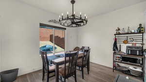 Dining space featuring dark wood-style flooring and a chandelier