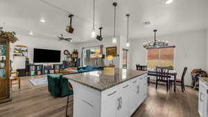 Kitchen with a breakfast bar area, dark stone countertops, a kitchen island, white cabinets, and dark wood-style floors
