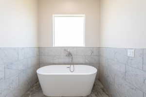Full bath with a soaking tub, a wainscoted wall, and tile walls
