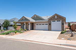 View of front of home featuring stone siding, a garage, concrete driveway, and a tiled roof