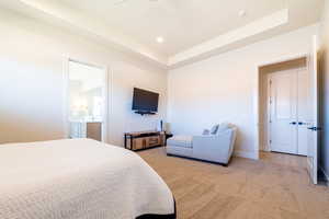 Bedroom with a tray ceiling, carpet flooring, ensuite bathroom, ceiling fan, and recessed lighting
