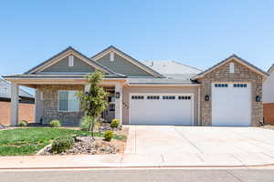View of front facade featuring stone siding, a garage, concrete driveway, and a front yard