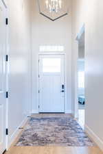 Entryway with suspended lighting, light wood-style flooring, and a high ceiling