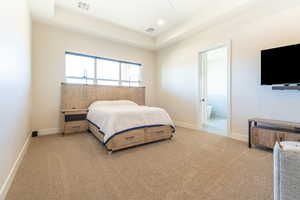 Bedroom with light carpet, ensuite bathroom, a ceiling fan, a tray ceiling, and recessed lighting