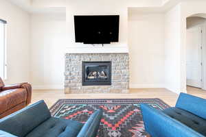 Living room featuring arched walkways, light wood-type flooring, and a fireplace