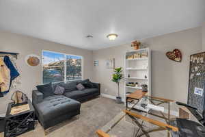 Carpeted living room featuring an office area and baseboards