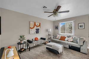 Living room with ceiling fan, carpet, and a textured ceiling