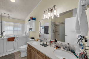 Bathroom featuring a bath, ornamental molding, double vanity, a shower stall, and a textured ceiling