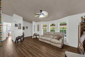 Living room featuring a ceiling fan and dark wood-style floors