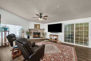 Living room featuring a fireplace, dark wood finished floors, and ceiling fan