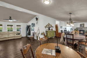Dining area with ceiling fan, dark wood finished floors, and a glass covered fireplace