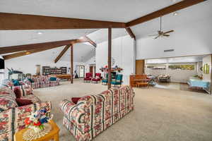 Carpeted living area featuring ceiling fan and a textured ceiling