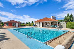 Community pool with a patio area and a shed