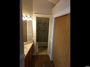 Bathroom with vanity, shower / bathtub combination with curtain, and dark colored carpet