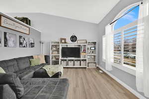 Living area with vaulted ceiling and light wood finished floors
