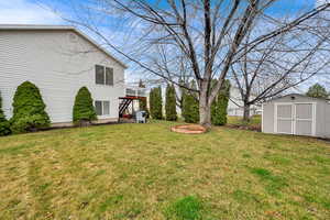 View of grassy yard with stairway and a storage shed