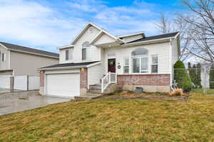 Tri-level home with a garage, brick siding, and concrete driveway