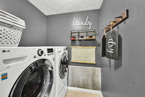 Laundry room with washer and clothes dryer and a textured ceiling