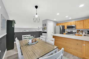 Kitchen featuring light countertops, stainless steel appliances, light wood-style floors, light wood finish cabinetry, and vaulted ceiling