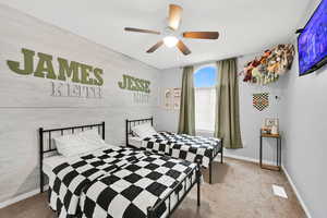 Bedroom featuring carpet floors, wood walls, and ceiling fan