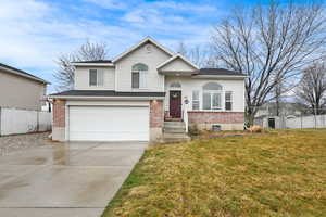 Split level home with a garage, driveway, and brick siding